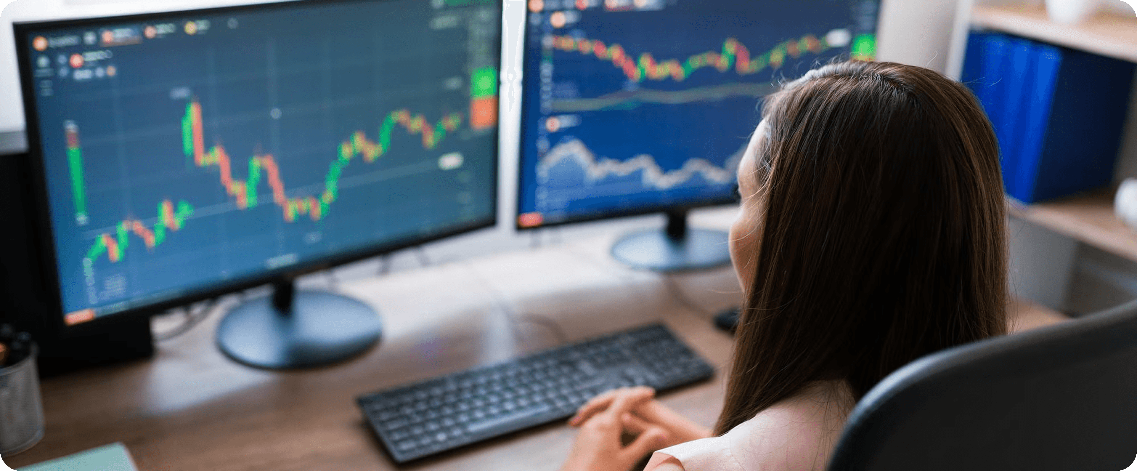 Trader analysing markets on dual monitors